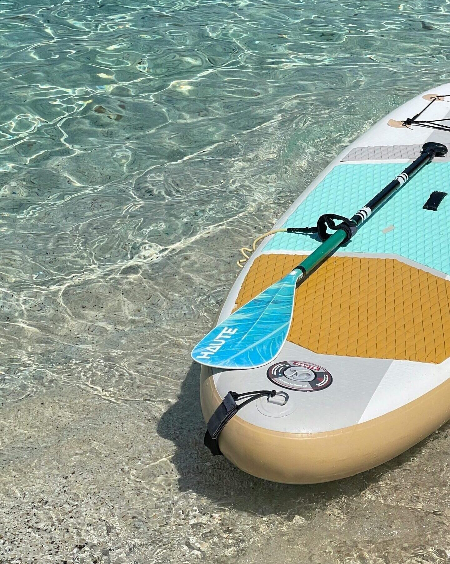 A paddleboard on a clear water beach, representing leisure and summer activities.